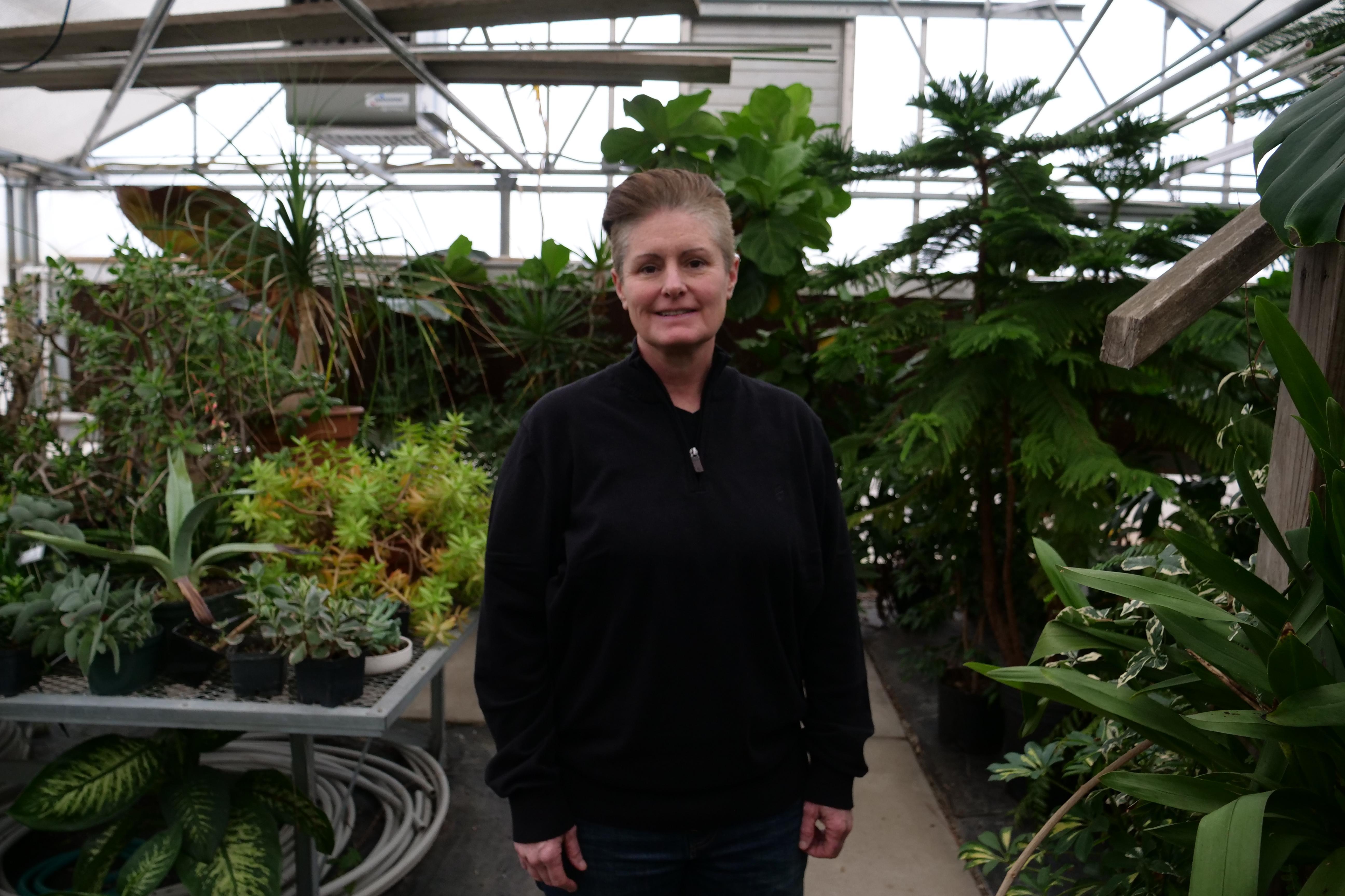 Never Quit Service Award winner Amy Coonce inside a greenhouse smiling at the camera.